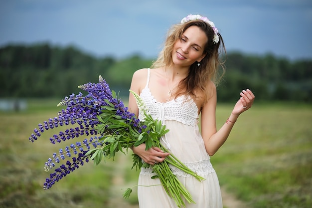 Mooi meisje met een boeket blauwe bloemen op de natuur in de zomer