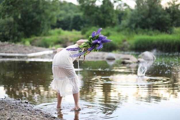 Mooi meisje met een boeket blauwe bloemen op de natuur in de zomer