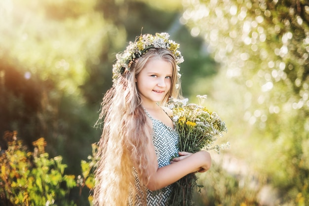 Mooi meisje met een boeket van wilde bloemen en een krans in het haar