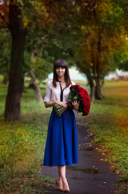 Mooi meisje met een groot boeket bloemen. Vrouw die lacht en een roos houdt