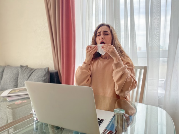 Mooi meisje met een laptop aan tafel leest het nieuws over de uitbraak van het coronavirus