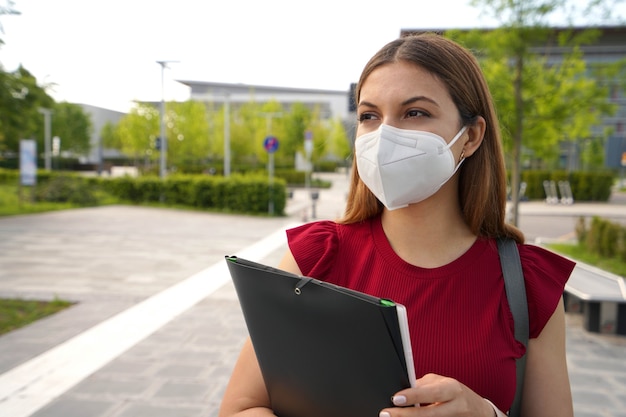 Mooi meisje met FFP2 KN95 gezichtsmasker met mappen die naar de zijkant buiten kijken