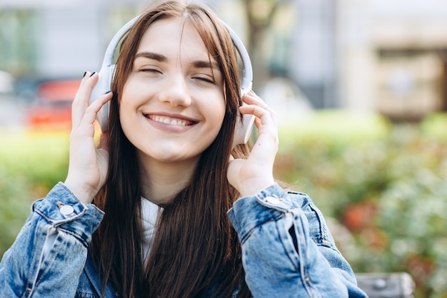 Mooi meisje met gesloten ogen in hoofdtelefoons, oprecht glimlachend, genietend van uw favoriete muziek