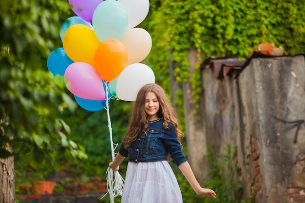 Mooi meisje met grote kleurrijke ballonnen die naar beneden loopt in de oude stad