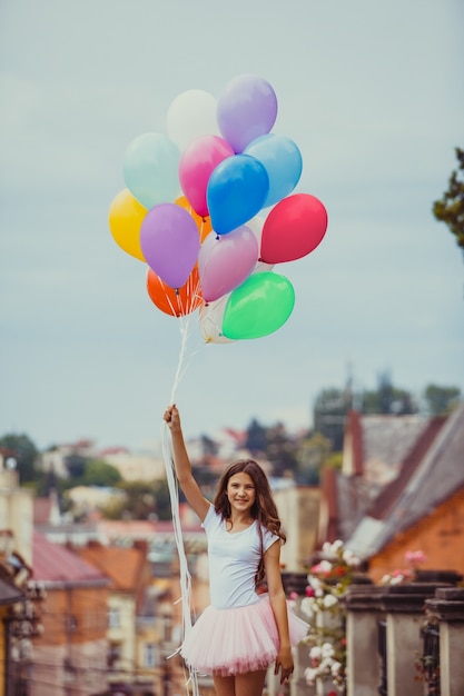 Mooi meisje met grote kleurrijke latex ballonnen poseren in de straat van een oude stad