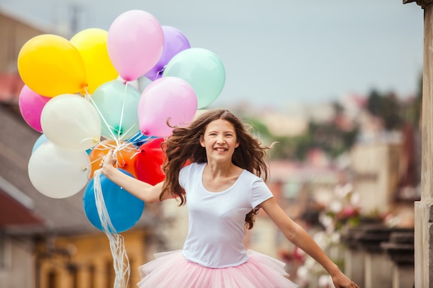 Mooi meisje met grote kleurrijke latex ballonnen poseren in de straat van een oude stad