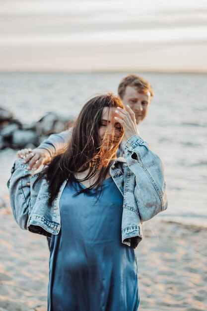 Mooi meisje met haar vriendje loopt op het strand. Lange haren wapperen in de wind.