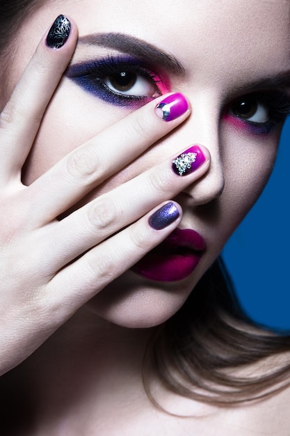 Mooi meisje met heldere creatieve mode-make-up en kleurrijke nagellak Art beauty design