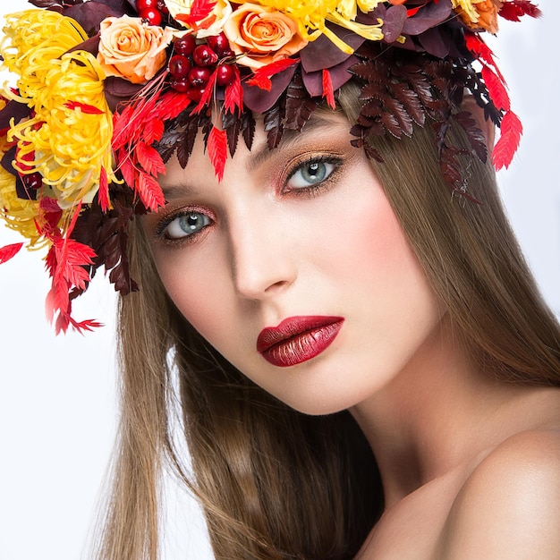 Mooi meisje met heldere herfstkrans van bladeren en bloemen Schoonheidsgezicht Foto genomen in de studio op een witte achtergrond