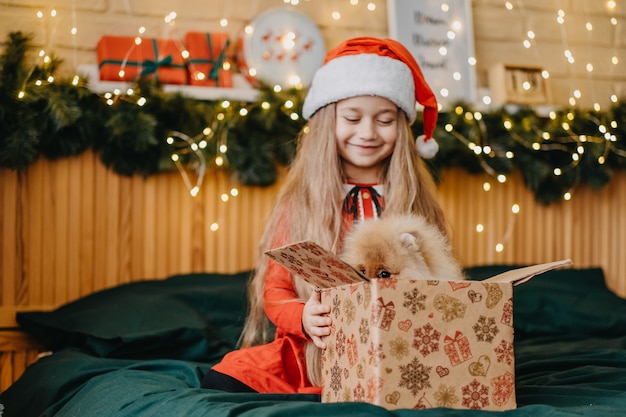 Mooi meisje met kerstmuts kreeg een puppy als cadeau voor nieuwjaar, kerstmagie en wonder, dromen komen uit