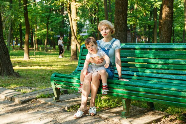 Mooi meisje met kinderen zit op een bankje in het park