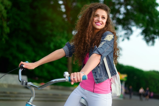 Mooi meisje met krullend haar op een fiets in de stad