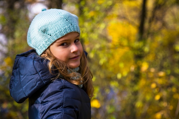 Mooi meisje met lang blond haar in het herfstpark. bruinogig meisje met gouden lokken op een achtergrond van gele herfstbladeren