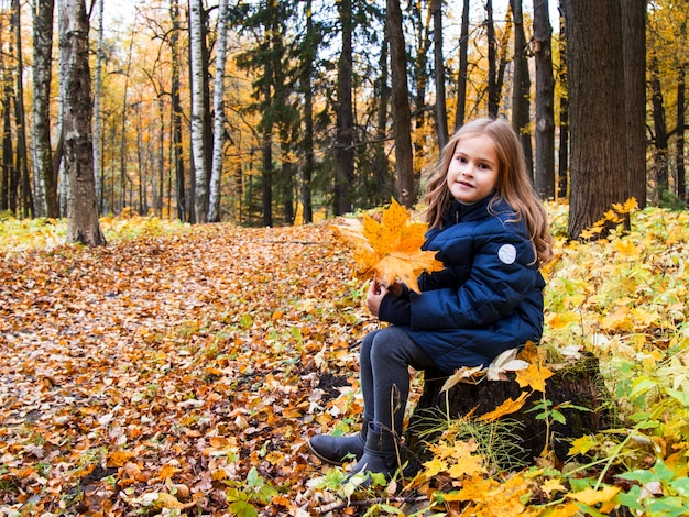 Mooi meisje met lang blond haar in het herfstpark. Bruinogig meisje met gouden lokken op een achtergrond van gele herfstbladeren