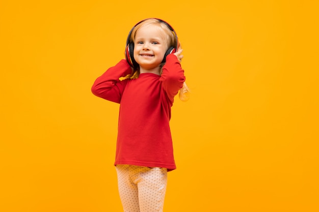 Mooi meisje met lang haar glimlacht en luistert naar muziek, foto geïsoleerd op geel