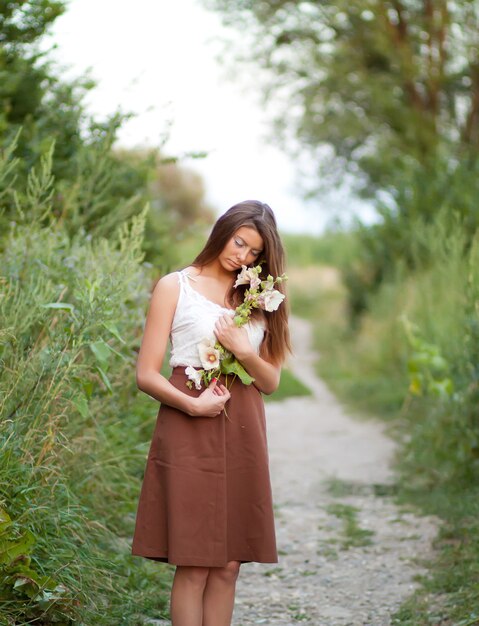 Mooi meisje met lang haar in het veld met bloemen