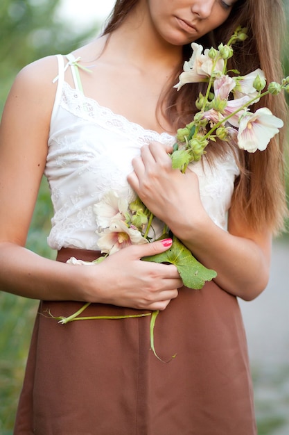 Mooi meisje met lang haar in het veld met bloemen