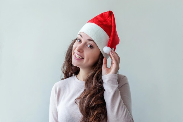 Mooi meisje met lang haar in rode kerstman hoed geïsoleerd op een witte achtergrond op zoek gelukkig en opgewonden jonge vrouw portret ware emoties Happy Christmas en Nieuwjaar vakantie