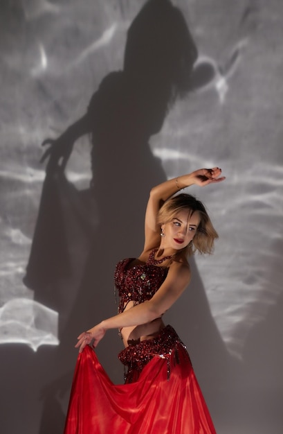Mooi meisje met lang zwart haar in een rode oosterse jurk dansen buikdans in de studio kamer Arabische cultuur
