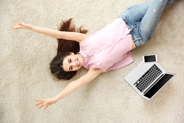 Mooi meisje met laptop die op vloer liggen
