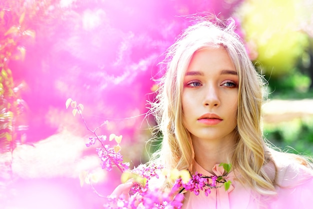 Mooi meisje met naakt make-up poseren in lentetuin Portret van blonde jonge vrouw met blauwe ogen in natuurlijke scène Mooie fee dwalen tussen bloeiende bomen charme van lente concept