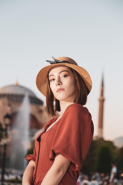 Mooi meisje met oranje gekleurde jurk poseren met Sultan Ahmet Moskee tijdens zonsondergang vanuit Istanbul