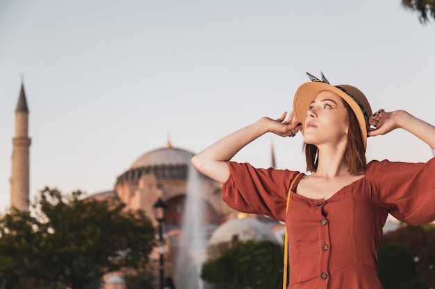 Mooi meisje met oranje gekleurde jurk poseren met Sultan Ahmet Moskee tijdens zonsondergang vanuit Istanbul