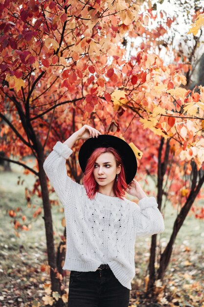 Mooi meisje met rood haar en hoed die in het park, de herfsttijd lopen.