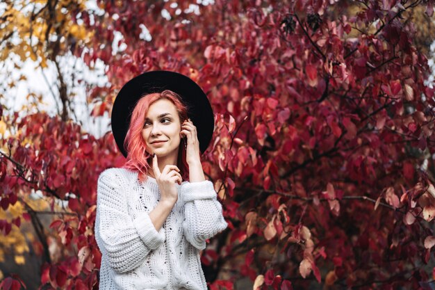 Mooi meisje met rood haar en hoed die in het park, de herfsttijd lopen.