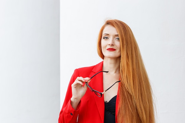 Mooi meisje met rood haar gekleed in een rood pak Zakelijk portret