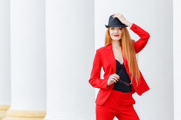 Mooi meisje met rood haar gekleed in een rood pak Zakelijk portret