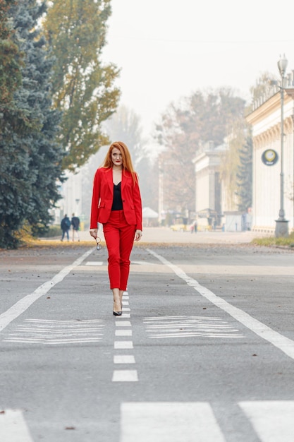 Mooi meisje met rood haar gekleed in een rood pak Zakelijk portret