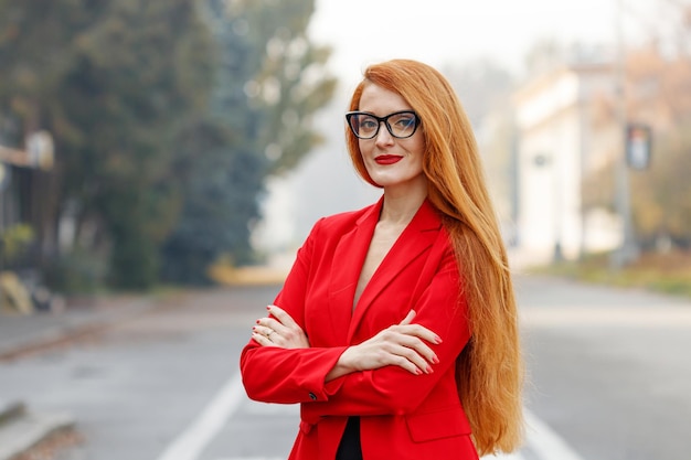 Mooi meisje met rood haar gekleed in een rood pak Zakelijk portret