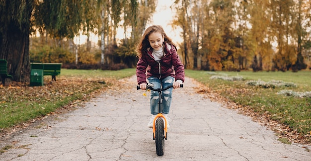 Mooi meisje met rood haar rijdt op de fiets in het park tijdens een herfstwandeling