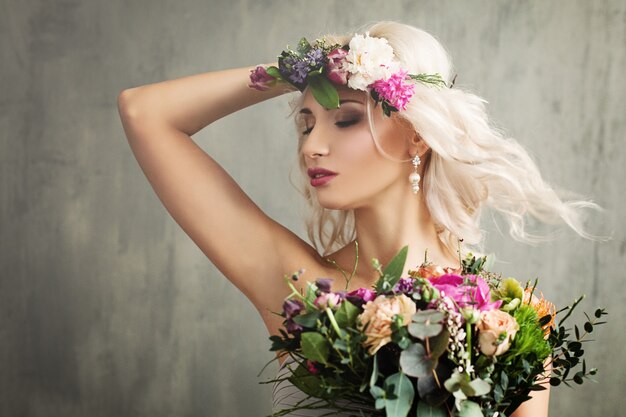Foto mooi meisje met zomerbloemen, make-up en krullend haar