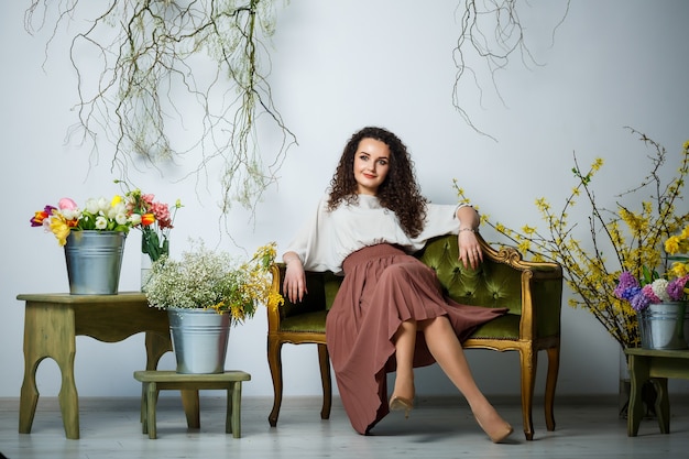 Mooi meisje model met krullen in een jurk poseren in mooie arrangementen. Het begin van de lente met bloemen