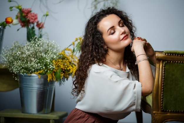 Mooi meisje model met krullen in een jurk poseren in mooie arrangementen. Het begin van de lente met bloemen