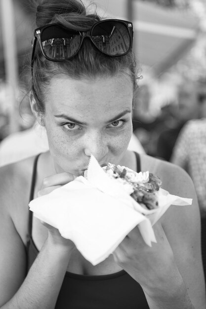 Mooi meisje of vrouw die sandwich-gyros eet Meisje met plezier eet hamburger na het dieet Ze opende haar mond met een gyros op zijn uitgestrekte handen en sloot haar ogen