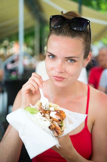 Mooi meisje of vrouw die sandwichgyros eten. meisje eet met plezier hamburger na dieet. ze opende haar mond, hield een gyros op zijn uitgestrekte handen en sloot haar ogen.