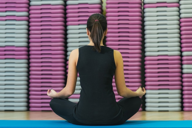 Mooi meisje op de mat die yoga, achtermening doet