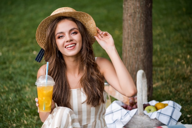 Mooi meisje op de picknick in het park het drinken limonade en het glimlachen