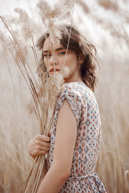 Mooi meisje op een gebied met lang gras in de herfst. kunstportret van een vrouw