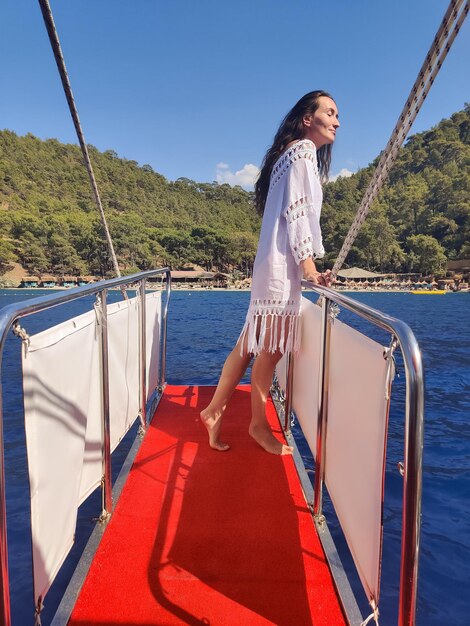Mooi meisje op het dek van een boot tijdens het reizen op zee met uitzicht op de bergen