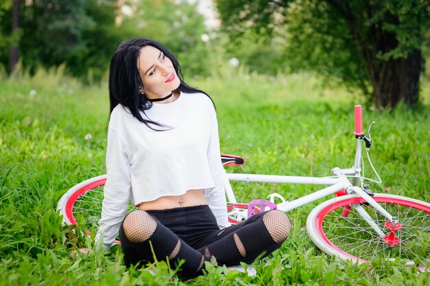 Mooi meisje poseren op een fiets. witte en rode fiets. wandelen in de natuur. gezonde levensstijl. weekend in de natuur Portret van een gelukkig mooi meisje in een wit T-shirt. plek om te schrijven