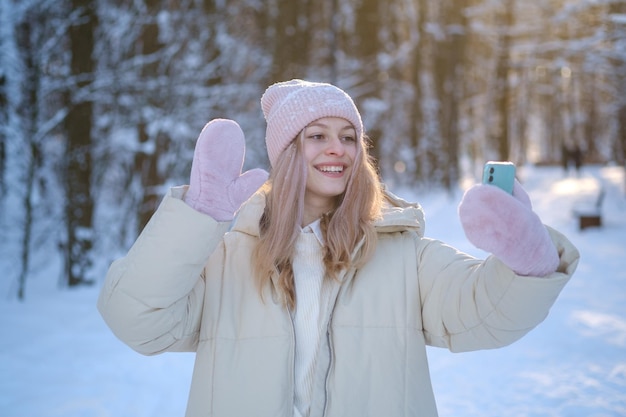 Mooi meisje praten met vrienden via videocommunicatie in een prachtig winterbos