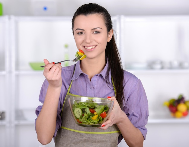 Mooi meisje probeert een gezonde en smakelijke salade.