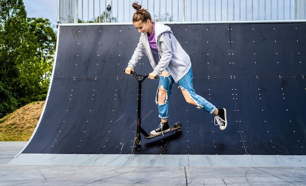 Mooi meisje scooter rijden op helling in park schattige tiener met eco-voertuig buitenshuis