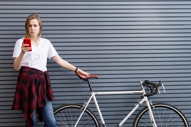 Mooi meisje staat met een fiets op de achtergrond van een muur