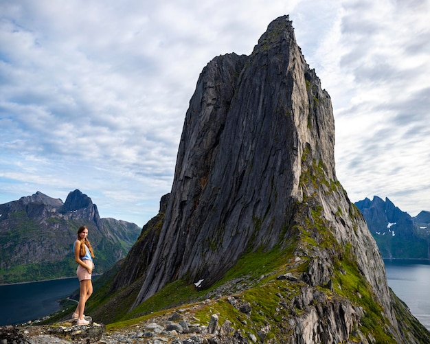 mooi meisje staat op de rotsen boven de afgrond en geniet van het uitzicht op de segla, noorwegen, senja