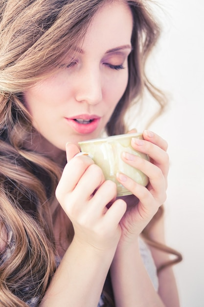 Foto mooi meisje warme koffie drinken in de ochtend op een witte achtergrond.